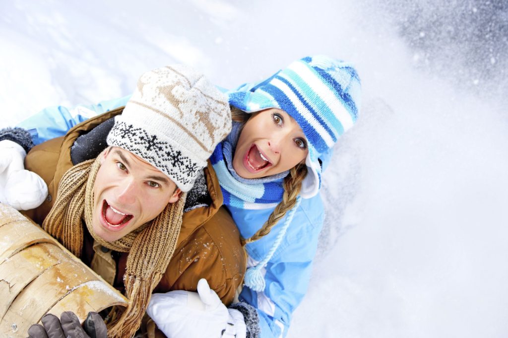 Young happy smiling couple sledging. Winter